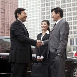 two-businessmen-shaking-hands-next-to-a-car-2021-08-26-15-29-13-utc